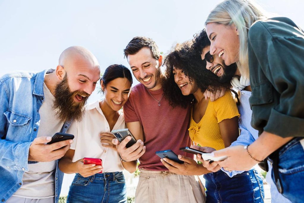 Group of happy people smiling while using a mobile phone